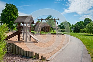 Children`s playground equipped with wooden swings and slides.
