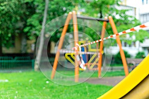 Children`s playground on the grass in the park wrapped with red barrier tape. Prohibition of outdoor walks photo