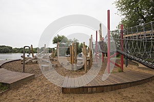 Children`s playground made of environment, eco-friendly materials. Wooden tree trunk sides, swings, net bridges, climbers.