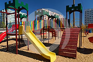 children`s playground next to a condominium. Swing, slide, stairs, multistory