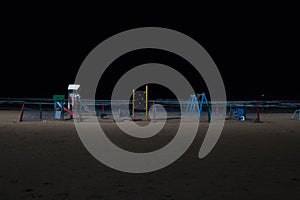 A children`s playground in the sand of the beach of Essaouira at night illuminated with spotlights