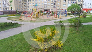A children\'s playground with slides, swings and a sandbox is located among residential buildings in the city quarter