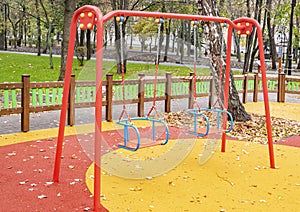 Children`s playground with a swing in the autumn park