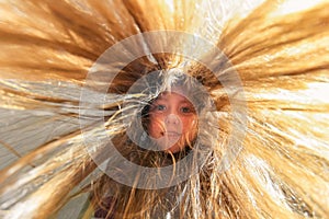 Children`s portrait wide-angle photo. Portrait of a cheerful little girl with her hair flying in the wind and sun. Bottom view. A