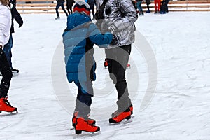 Children`s rink. The instructor teaches the teenager boy to skate. Active family sport during the winter holidays.