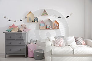 Children`s room with house shaped shelves, sofa and chest of drawers. Interior design