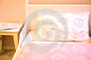 Children`s room with pink walls, wooden floor, bed with pillow and blankets