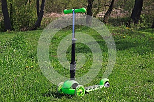 Children`s scooter on a green lawn. Summer season for walks in nature or in the park