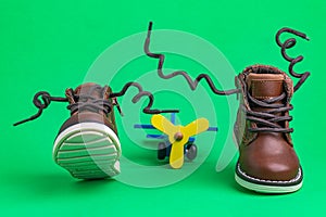 Children`s shoes for a boy made of leather with laces on a green background. Children`s toy - an airplane