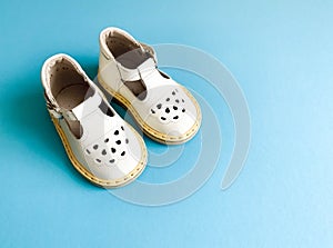 Children`s shoes, the concept of the first step. Baby white on a blue background. Space for the text. The first steps of t
