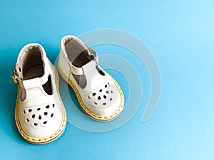 Children`s shoes, the concept of the first step. Baby white on a blue colored background. Space for the text. The first steps of t