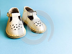 Children`s shoes, the concept of the first step. Baby white on a blue colored background. Space for the text. The first steps of t