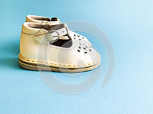 Children`s shoes, the concept of the first step. Baby white on a blue colored background. Space for the text. The first steps of t