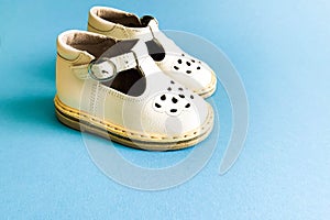 Children`s shoes, the concept of the first step. Baby white on a blue colored background. Space for the text. The first steps of t