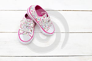 Children`s shoes for girls in florets on a wooden background. Fl