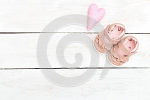 Children`s shoes pink color for baby on a white wooden backgroun