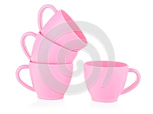 Children`s small pink mugs stand on top of each other on a white background. Toy set made of plastic. The concept of a tea party.