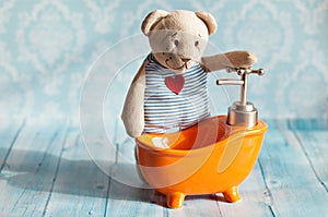 Children's soft toy teddy bear is bathed in orange bath doll house. Blue bathroom to . Playing with dolls in the family