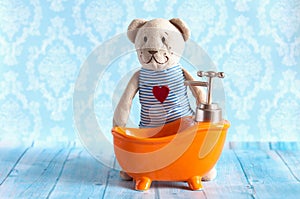 Children's soft toy teddy bear is bathed in orange bath doll house. Blue bathroom to . Playing with dolls in the family