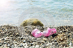 Children`s summer slippers lie near the beach