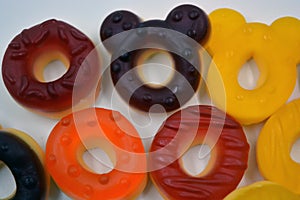 Children\'s sweets in the form of multi-colored donuts, chewable, gelatin sweets are located on a white background.