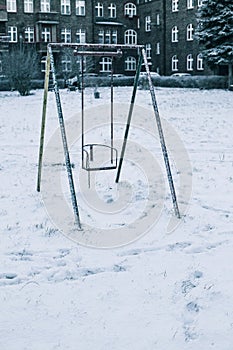 children\'s swing covered with snow on the playground in winter