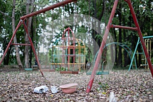 Children`s swings hang empty an idle at a playground on a dull, overcast day. Lost child day