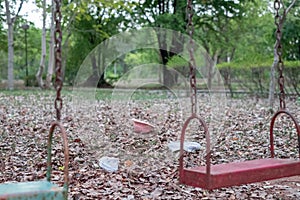 Children`s swings hang empty an idle at a playground on a dull, overcast day. Lost child day