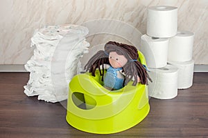 Children`s toilet pot green, nappies and toilet paper, the concept of the baby`s transition from diapers to the toilet