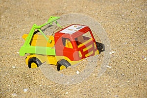 Children`s toy car, colorful plastic lorry on beach sand