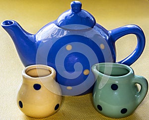 Children`s toy set of dishes with a teapot for tea on a yellow background.