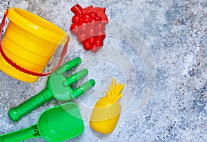 Children`s toys: bucket, shovel, rake on a stone background.