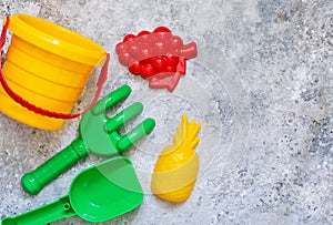 Children`s toys: bucket, shovel, rake on a stone background.