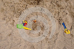 Children's toys - a scoop and a toy car lie on the sand on the beach. Top view