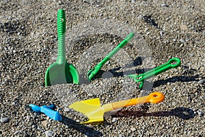 Children\'s toys on the seashore, multi-colored scoops, shovels and rakes lie on a rocky beach. Child safety concept