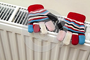 Children& x27;s warm hand knitted striped woolen gloves drying on hea