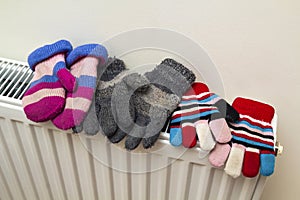 Children& x27;s warm hand knitted striped woolen gloves drying on hea