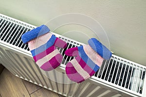 Children& x27;s warm hand knitted striped woolen gloves drying on hea