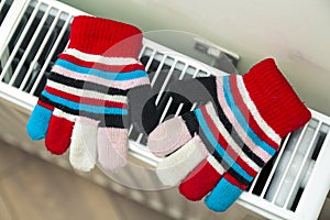 Children& x27;s warm hand knitted striped woolen gloves drying on hea