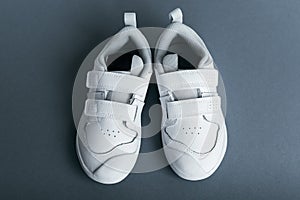 Children`s white sports leather sneakers on a dark blue