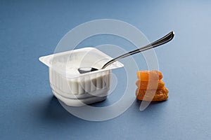 Children`s white yoghurt in a plastic cup and dried apricot