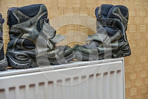 Children`s winter boots dry on the heater after getting wet in the rain