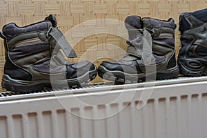 Children`s winter shoes dry on the heater after getting wet