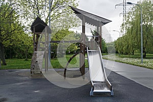 Children's wooden playground house with a slide in a public park after rain