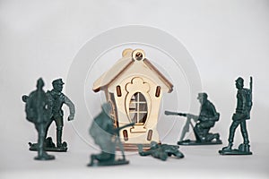 Children& x27;s wooden small house and plastic soldiers on a white background, warfare, children& x27;s game of war games