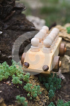 Children`s wooden toys. Children wooden car with passengers outdoors. Natural wood construction set