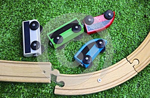 Children`s wooden train with cars, railway and wooden trees on artificial plastic green grass. Early childhood education,