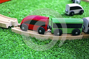 Children`s wooden train with cars, railway and wooden trees on artificial plastic green grass. Early childhood education,
