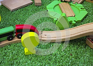 Children`s wooden train with cars, railway and wooden trees on artificial plastic green grass. Early childhood education,