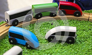 Children`s wooden train with cars, railway and wooden trees on artificial plastic green grass. Early childhood education,